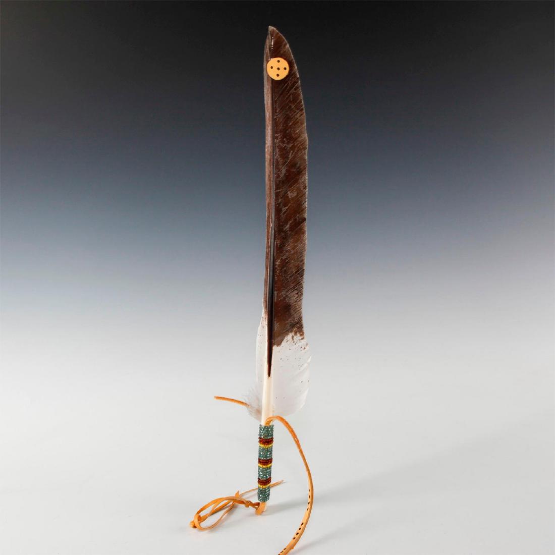 CLASSICAL NATIVE AMERICAN HEADDRESS ROACH: Made from a large tail feather and decorative adornments. Trimmed and adorned with feathers, painted leather thong and concho, as well as beads. The roach, a type of Native American headdress frequent