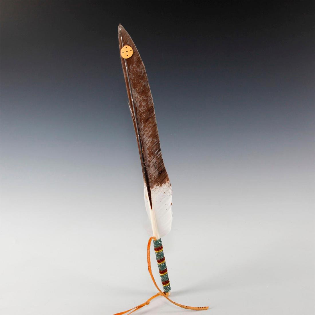 CLASSICAL NATIVE AMERICAN HEADDRESS ROACH: Made from a large tail feather and decorative adornments. Trimmed and adorned with feathers, painted leather thong and concho, as well as beads. The roach, a type of Native American headdress frequent