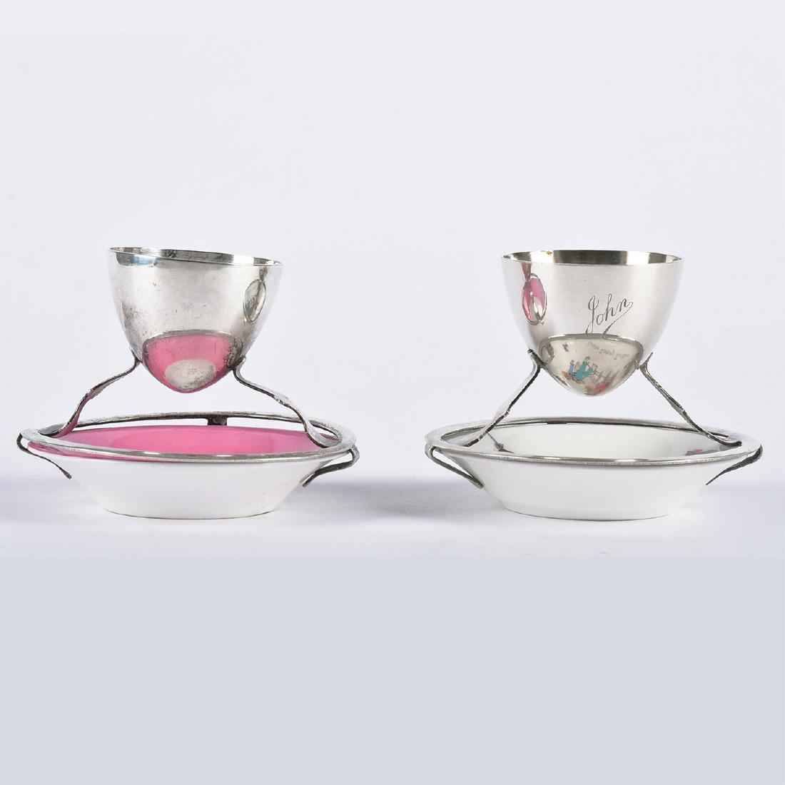 2 HALLMAKRED SILVER, PORCELAIN ROYAL DOULTON EGG CUPS: One from children's series Little Tommy Tucker and the one with a bright pink decoration. Hallmark and patent numbers to bottom of silver feet. Marked ROYAL DOULTON MADE IN ENGLAND to bottom. Issued: