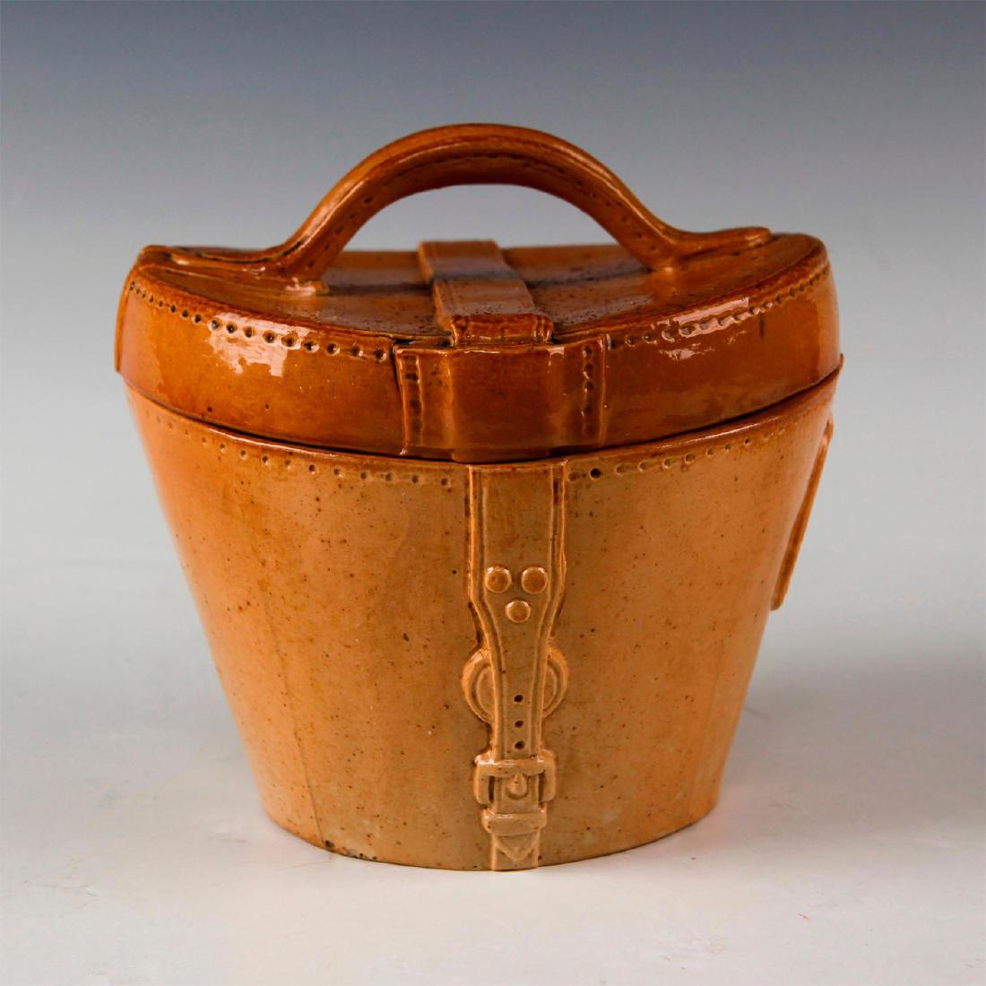 DOULTON LAMBETH LEATHER WARE STONEWARE, HAT BOX: Tan salt glaze, with lid sculpted as a hat box. Marked DOULTON LAMBETH ENGLAND. Issued: c. 1900 Dimensions: 5"H Manufacturer: Doulton Lambeth Country of Origin: England