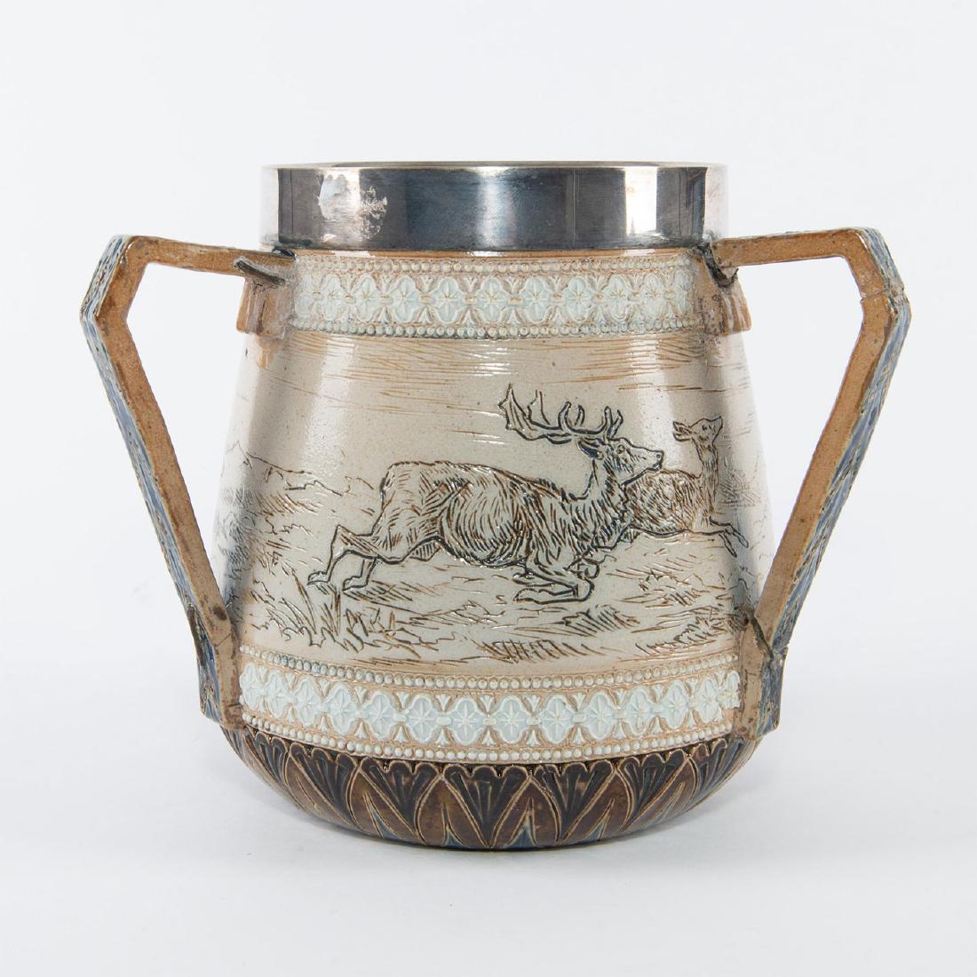 SIGNED HANNAH BARLOW DOULTON LAMBETH RIMMED TYG JUG: Sgraffito stag sketch in stoneware. Signed, impressed to bottom. Iconic sketchbook animal figures filled with rich ocher glaze, on a fair, sandy ground. Three handled 'tyg' style jug, inspired by the