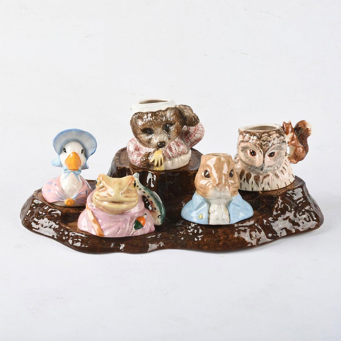 SET OF 5 BESWICK BEATRIX POTTER CHARACTER JUGS & STAND: Characters from Beatrix Potter children's books. Includes Beswick tree stump display stand, Old Mr. Brown, Jeremy Fisher, Mrs. Tiggy-Winkle, Peter Rabbit and Jemima Puddle-Duck. Figurines measure appr