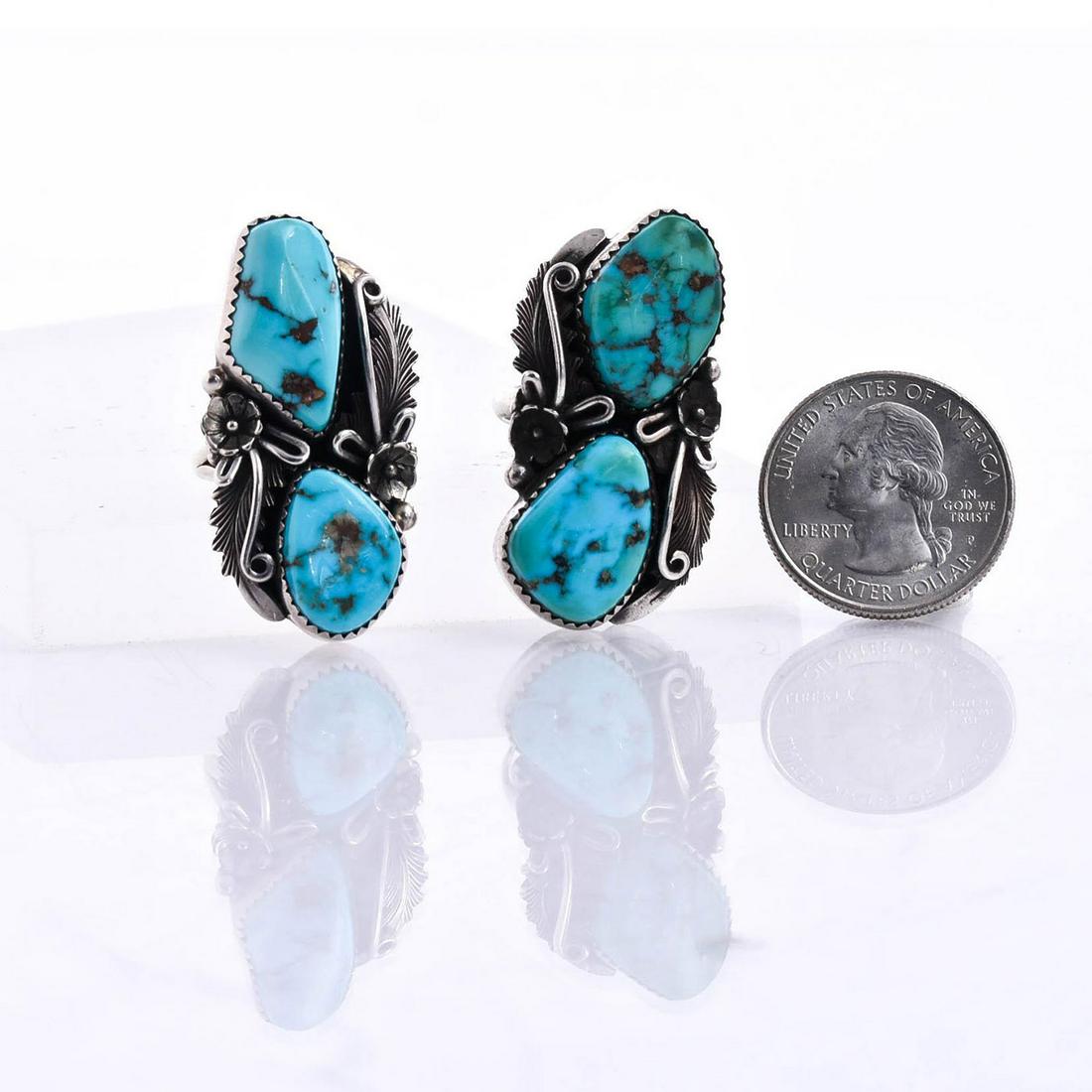 2 NATIVE AMERICAN NAVAJO SILVER TURQUOISE RINGS: Hallmarked silver, Navajo artist. Total weight approx. 25 grams. Cast silver with worked Native American designs. 6 ring size; 6 ring size. Artist: Peterson Johnson Issued: 20th c. Dimensions: 1.5"L, 