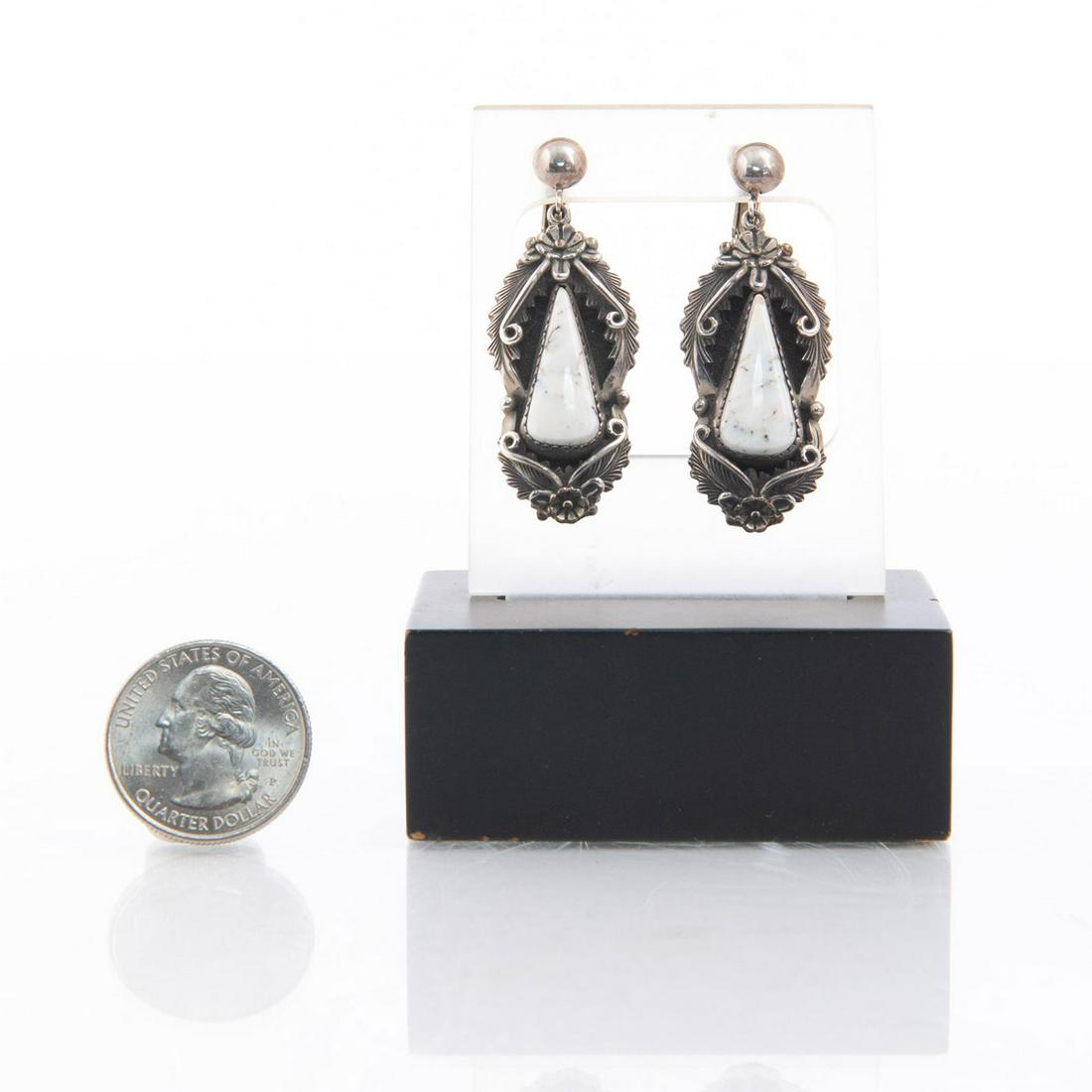 NAVAJO STERLING SILVER WHITE BUFFALO TURQUOISE EARRINGS: By Peterson Johnson. Triangular shaped stone. Approx. weight 17g. Marked on the underside. Artist: Peterson Johnson Issued: 20th c. Dimensions: 1.75" L Country of Origin: United States