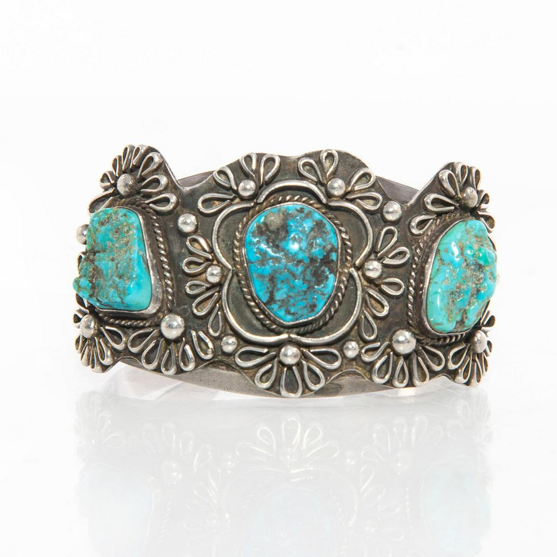 NAVAJO TURQUOISE SILVER BRACELET: Three inset turquoise stones with bead and floral design. Piece is hallmarked TD in three places. Total weight is approximately 85g. 6" circumference. Artist: Tom David Issued: 20th c. Dimensions: 2.7