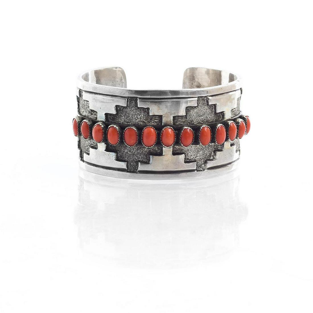 RICK MARTINEZ NAVAJO STERLING SILVER BRACELET: Cuff bracelet with geometric design and inset stones. Bracelet has 13 inset red coral stones. Signed R. Martinez and marked NAVAJO and sterling on reverse. Total weight is approximately 94 grams. 6.25