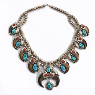 NAVAJO STERLING SILVER SQUASH BLOSSOM NECKLACE: Necklace with bear claws, turquoise, and red coral. Silver bead necklace with ten bear claws, ten pieces of turquoise, and ten pieces of red coral. Silverwork features floral, bead, rope, and geometri