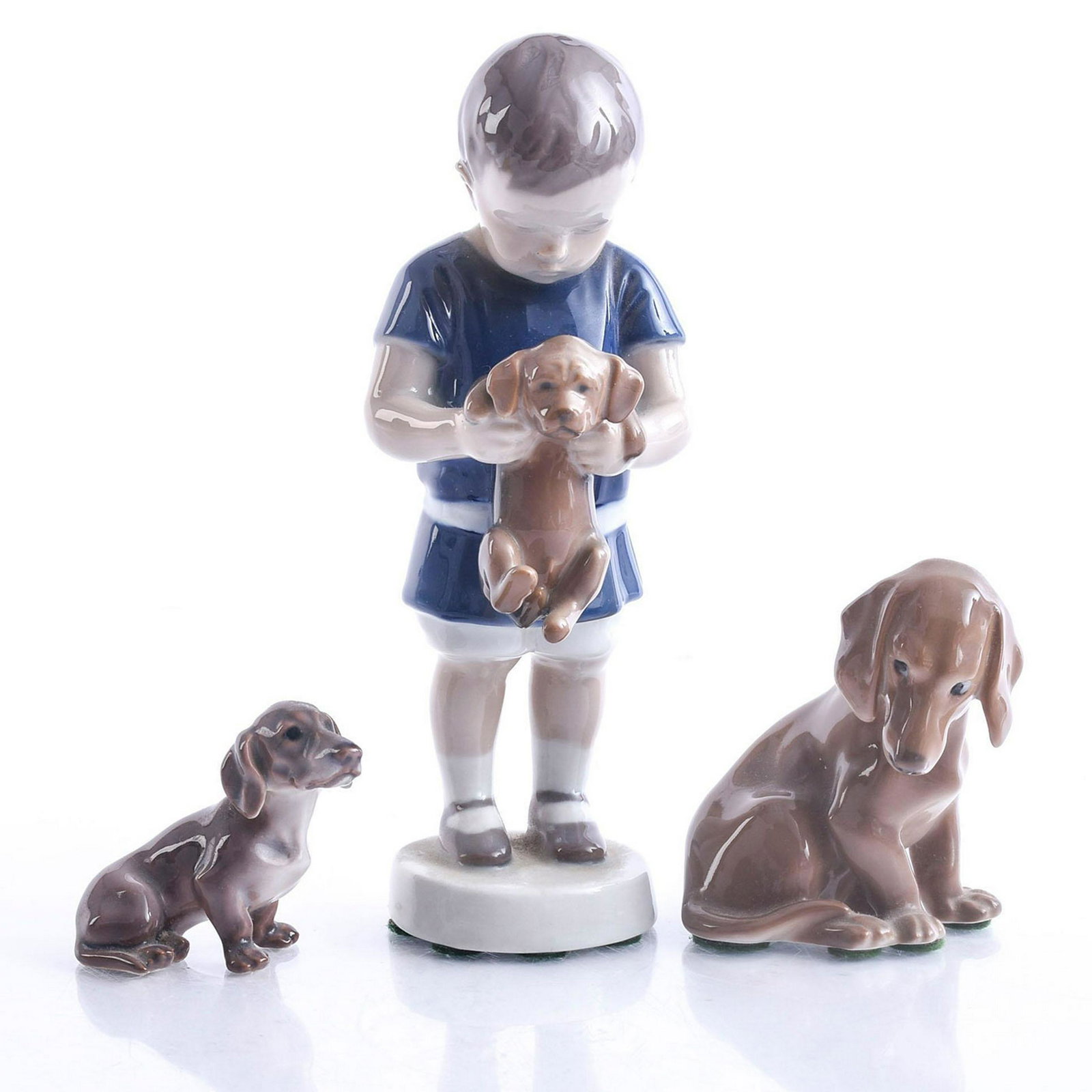 2 DUTCHHOUNDS AND LITTLE BOY HOLDING DUTCHHOUND: Bing and Grondle figurines. Dutchhound B&G dogs w. young boy. Issued: 20th c. Dimensions: 7"H Manufacturer: B&G Country of Origin: Denmark