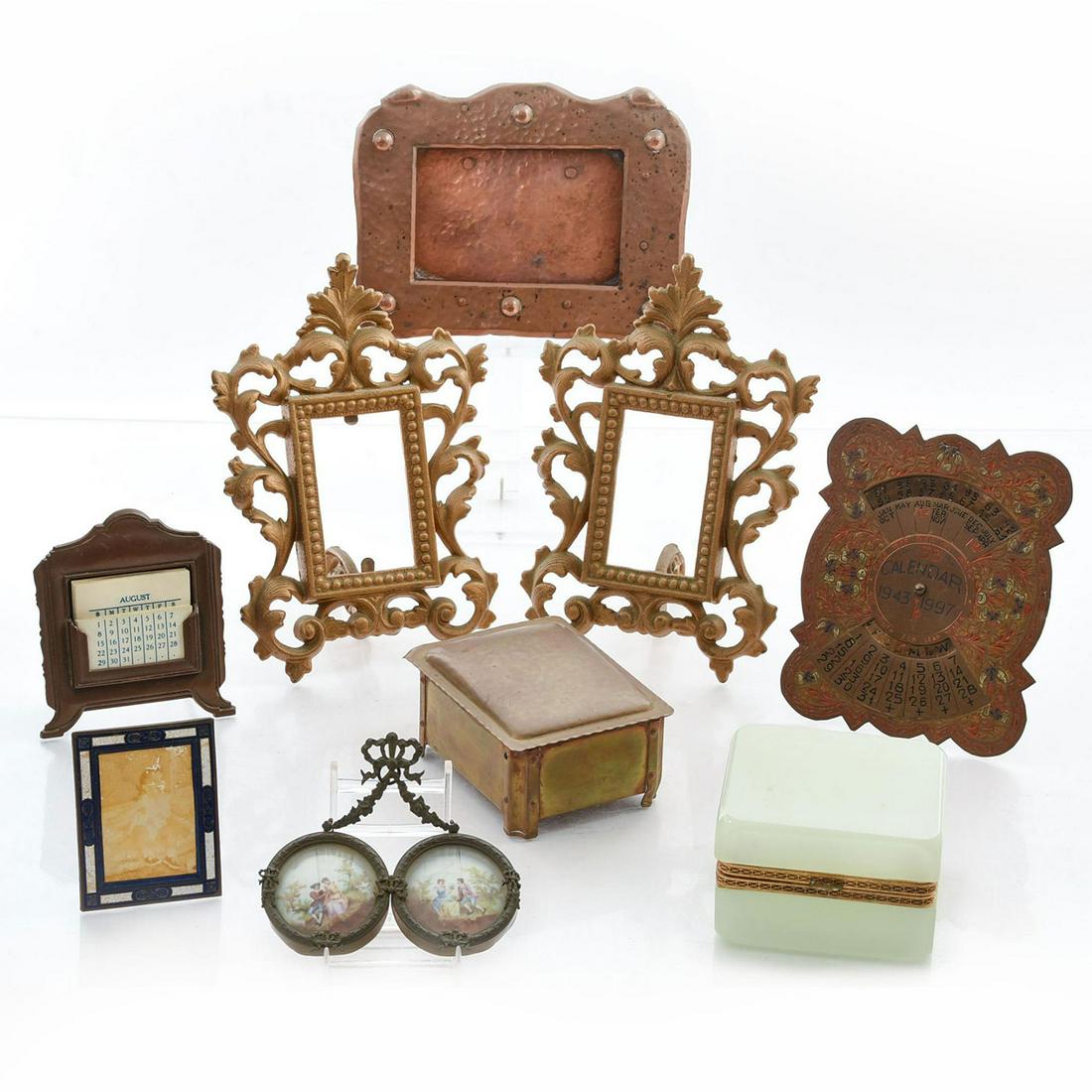 9 BRASS OR BRONZE DESK PIECES: Music box, carved stone box, 5 picture frames, 2 calendars. 1893 universal calendar with celluloid cards; 1943-1947 automatic calendar with inlaid enamel. Issued: 19th-20th c. Dimensions: 7.5"L, large