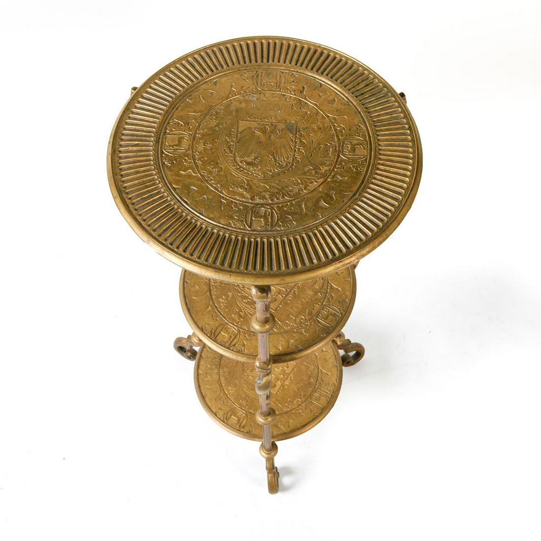 BYZANTINE REVIVAL BRONZE THREE TIER END TABLE: Displaying central image of Hapsburg Austrian two headed eagle. A continental Byzantine Revivial three tier bronze stand with circular shelves, each centering a relief armorial shield depicting double