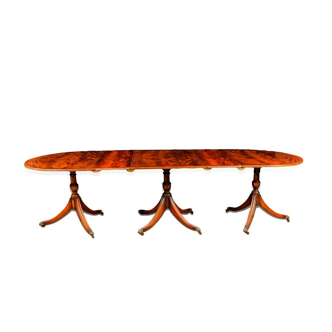 GEORGIAN STYLE THREE PEDESTAL DINING TABLE: Crotched veneer construction, expandable with 2 leaves. Mid century reproduction of a Georgian style dining table. Outer pedestals have 3 legs and the center has 4. Each leg is on casters. Leaves lock
