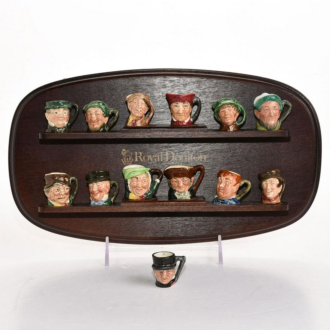 13 ROYAL DOULTON TINY CHARACTER JUGS, W. DISPLAY STAND: Glazed ceramic stoneware, various artists and colorways. Arry, Arriet, John Peel, Paddy, Mr. Pickwick, 2 Auld Mac, Sairey Gamp, Old Charley, Fat Boy, Sam Weller, Mr. Micawber, Cardinal. Artist: Harry