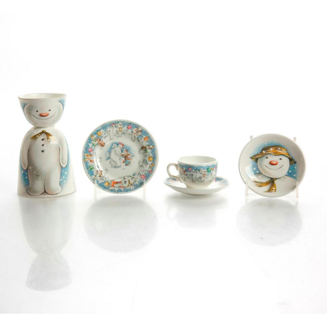 ROYAL DOULTON BREAKFAST SERVICE, JAMES AND THE SNOWMAN: Egg cup, plates and tea cup inspired by the British holiday book. A five piece Royal Doulton breakfast service including an egg cup, a tea cup, and three small plates. Hand decorated with characters a