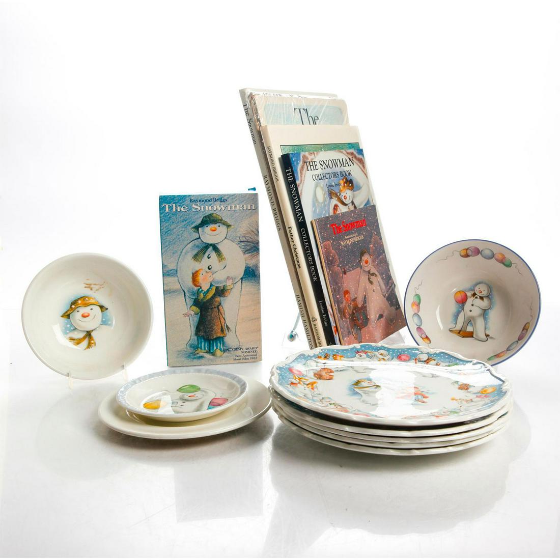 THE SNOWMAN BY RAYMOND BRIGGS COLLECTORS GROUP 15 ITEMS: Royal Doulton bone china plates and bowls. Five books. VHS tape. This is a very unusual collectors grouping inspired by the 1978 British holiday classic book The Snowman by Raymond Briggs. It includes