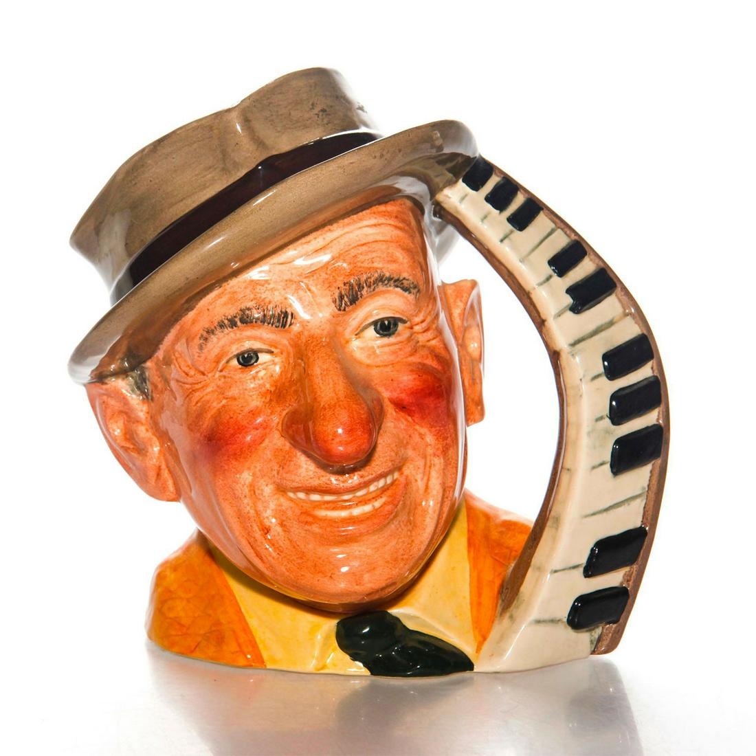 JIMMY DURANTE D6708 - LARGE - ROYAL DOULTON CHARACTER: Piano keyboard handle. With yellow jacket, and gray & black hat. Artist: David Biggs Issued: c. 1985 Dimensions: 8"H x 7.5"W Manufacturer: Royal Doulton Country of Origin: England