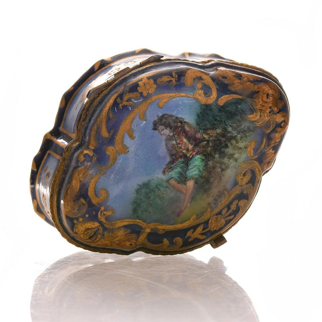 FRENCH PORCELAIN PILL BOX, IN THE STYLE OF SEVRES: Hand painted porcelain, with Sevres mark to bottom. Small hairline crack to top. Issued: 19th - 20th c. Dimensions: 3"L x 2.25"D x 2"H Country of Origin: France