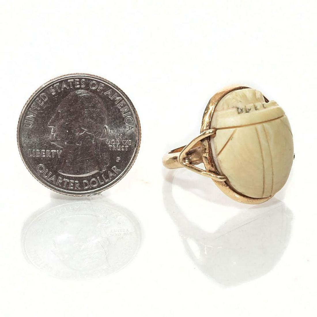 14 KARAT GOLD SCARAB BEETLE RING WITH NATURAL MATERIAL: Cream colored naturalistic stone in Neo Egyptian setting. Dimensions: Size 8.25 Country of Origin: United States