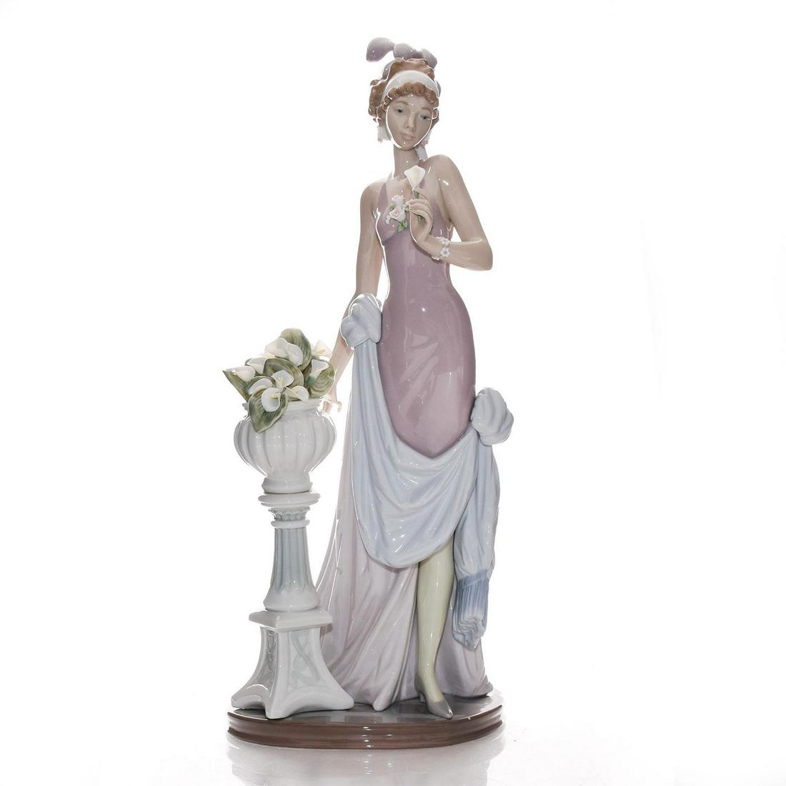 LARGE LLADRO FIGURINE, A TOUCH OF CLASS 01005377: Woman standing by a jardiniere of calla lilies. Porcelain; glazed. Pink and lavender colorway. Lladro backstamp. Includes box. Artist: Jose Puche Issued: 1986 Dimensions: 15"H Manufacturer: Lladro Cou