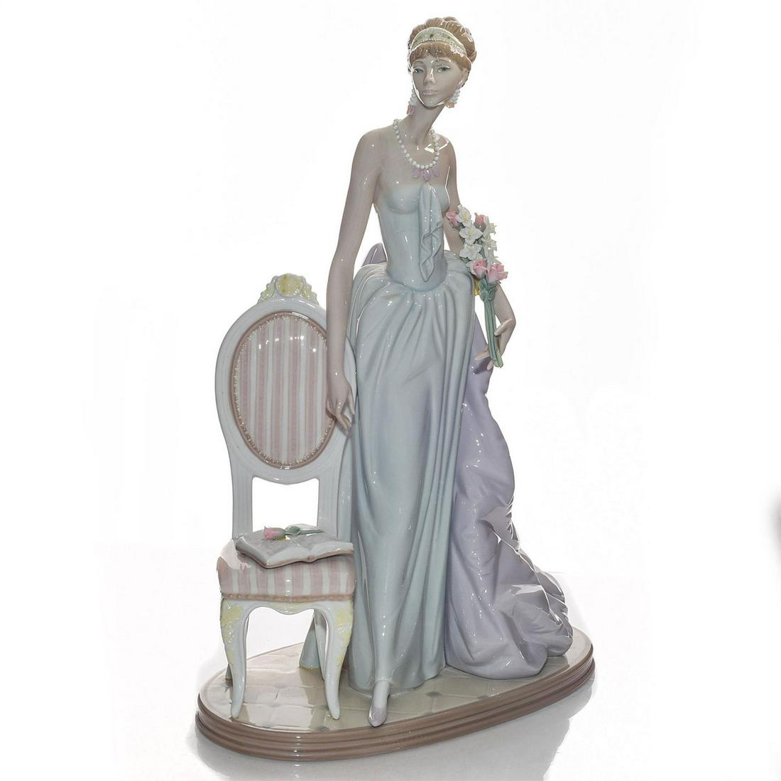 LARGE LLADRO LADY FIGURINE, A LADY OF TASTE 01001495: Glazed porcelain; high gloss. Handcrafted; hand painted. Woman wearing elegant dress with satin tail standing by chair. Exquisite floral detail. Artist: Jose Puche Issued: 1986 Dimensions: 15"H Manufa