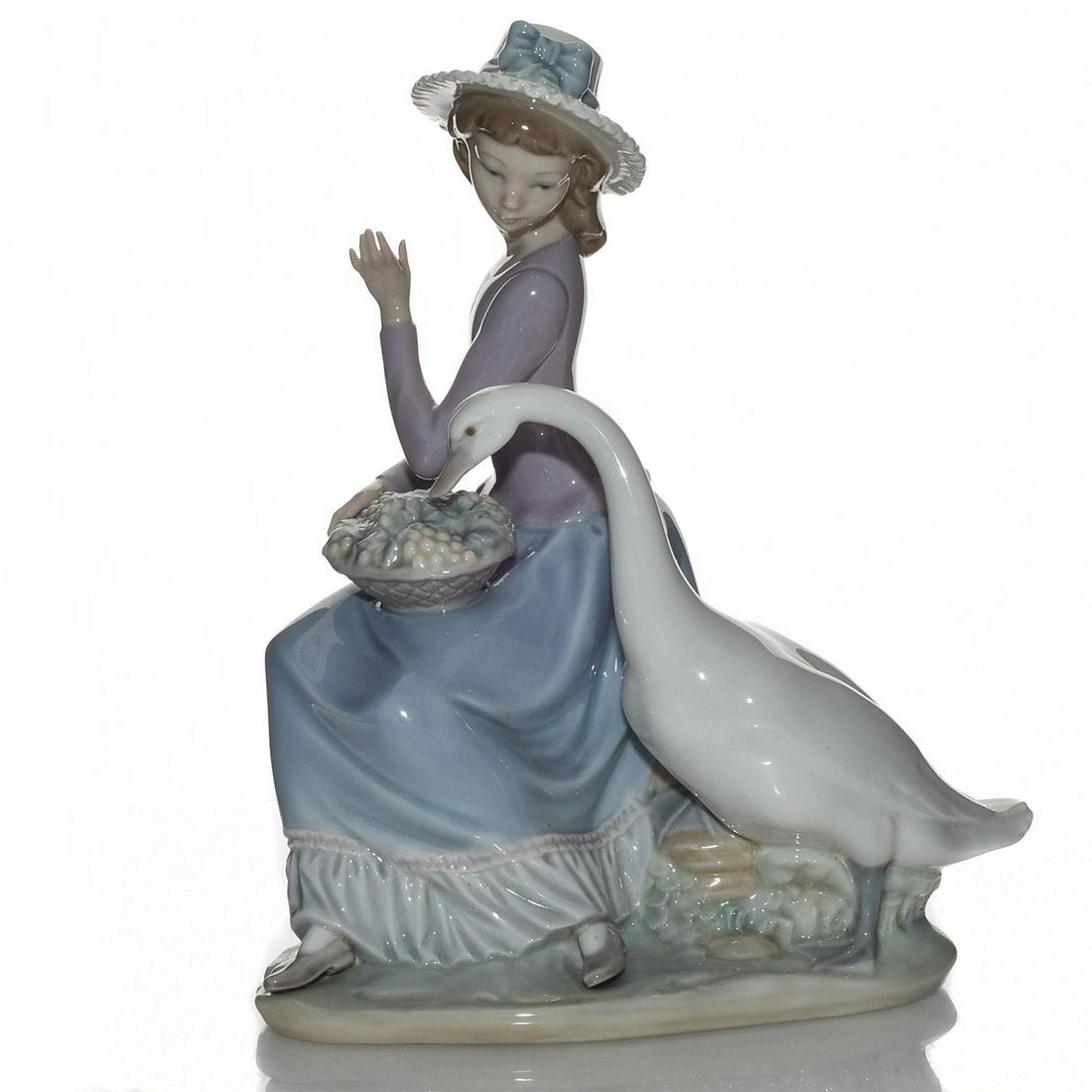 LLADRO FIGURINE, GOOSE TRYING TO EAT 01005034: Porcelain; glazed. Hand painted; handcrafted. Woman with goose. Lladro stamp on the underside. Artist: Vincente Martinez Issued: 1979-1996 Dimensions: 9.75"H Manufacturer: Lladro Country of Origin: Sp