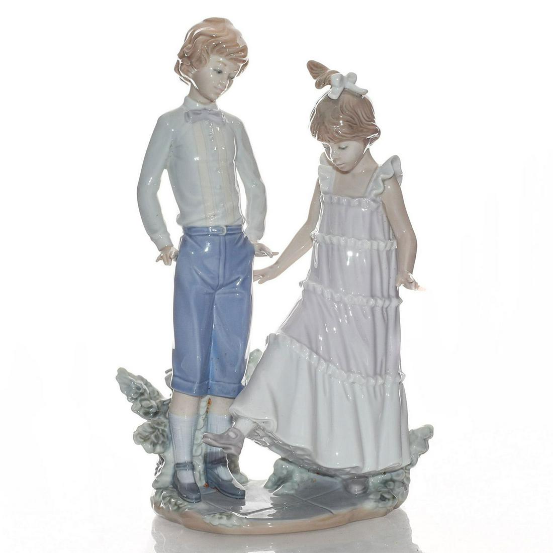LLADRO FIGURINE: ONE, TWO, THREE 01005426: Young children playing. Fine porcelain; glazed finish. Ensenando los zapatos. Lladro backstamp. Includes box. Artist: Jose Roig Issued: 1987-1995 Dimensions: 11"H Manufacturer: Lladro Country of Origi