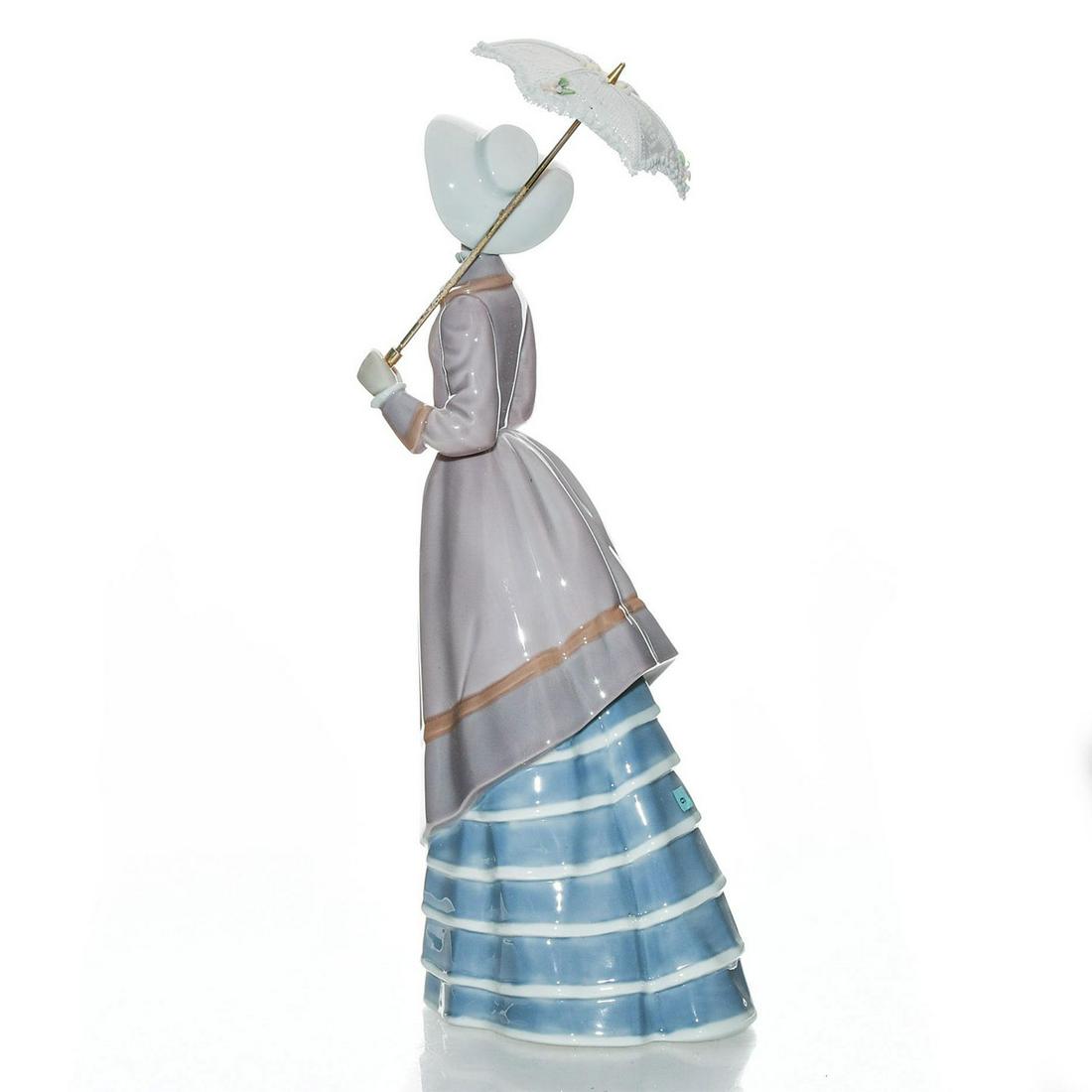 LLADRO LADY FIGURINE, PARISIAN LADY 01005321: Depicts young woman holding a parasol. Blue and pink colorway. Porcelain; glazed finish. Lladro backstamp. Includes box. Wear to box. Artist: Jose Puche Issued: 1985-1995 Dimensions: 9.75"H Manufactur