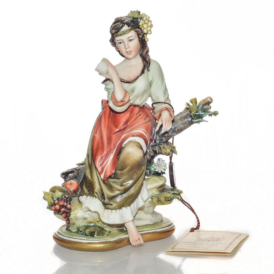 CAPODIMONTE ITALIAN CERAMIC LADY FIGURINE: Seated woman resting on tree limb. Porcelain; matte finish. Green and ochre colorway. Exquisite detail to piece. Capodimonte hand tag. Chip to leaves and figure's toes. Issued: 20th c. Dimensions: 7.5