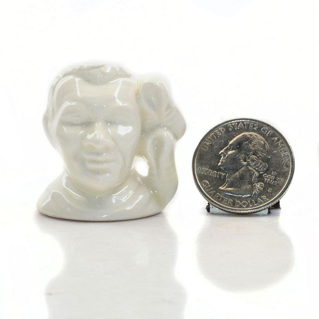 TINY ROYAL DOULTON CHARACTER JUG, JESSIE OWENS: Prototype ivory glazed ceramic jug. Doulton backstamp. Artist: Stanley Taylor Issued: 20th c. Dimensions: 1.5"H Manufacturer: Royal Doulton Country of Origin: England
