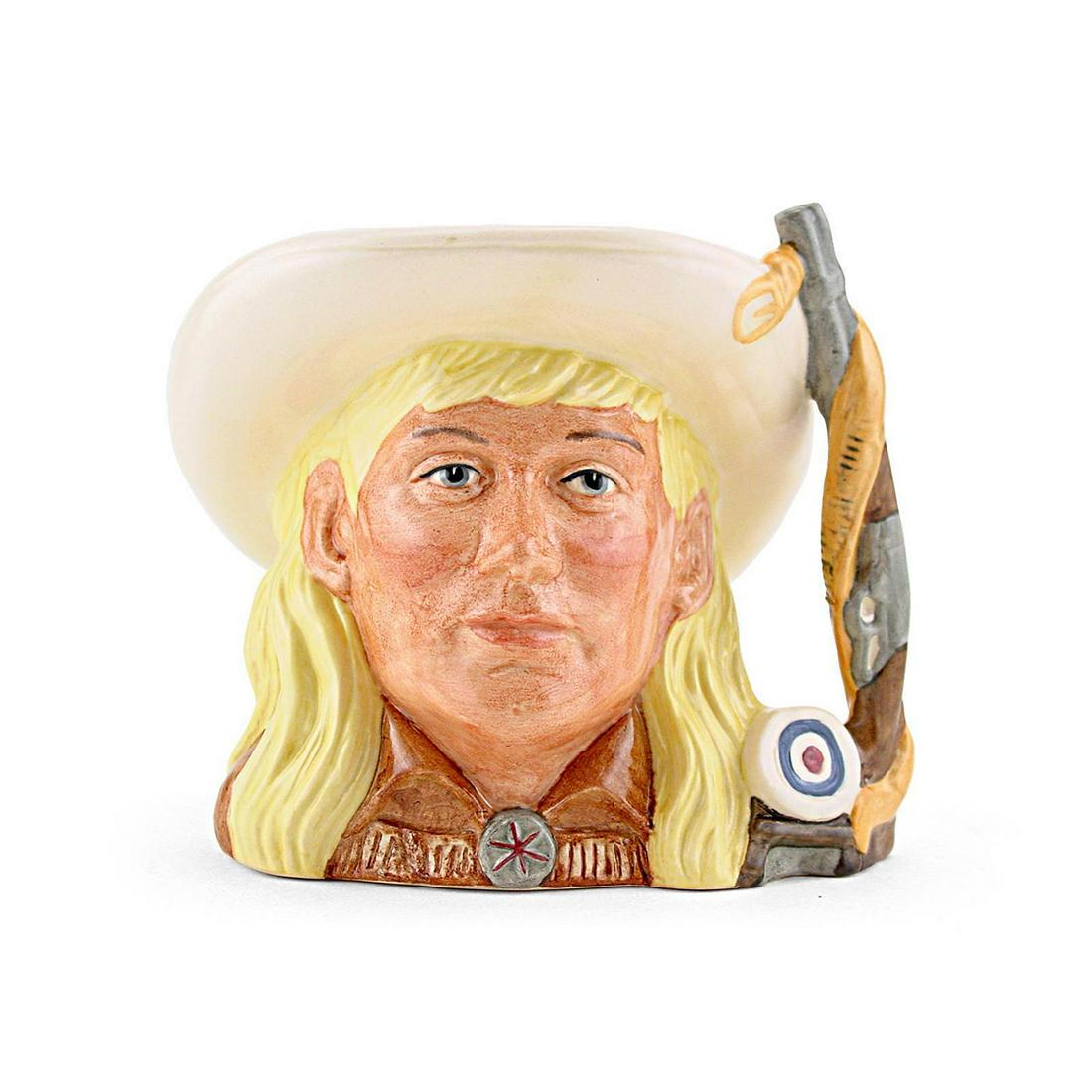 ANNIE OAKLEY D6732 - ODD SIZE - ROYAL DOULTON CHARACTER: Royal Doulton Character Jug, Annie Oakley D6732 (yellow hair; cream hat; brown tunic). Designed by Stanley J. Taylor. Series: The Wild West Collection, issued 1985 - 1989. Size: 5.25"H (odd)Phoebe Ann