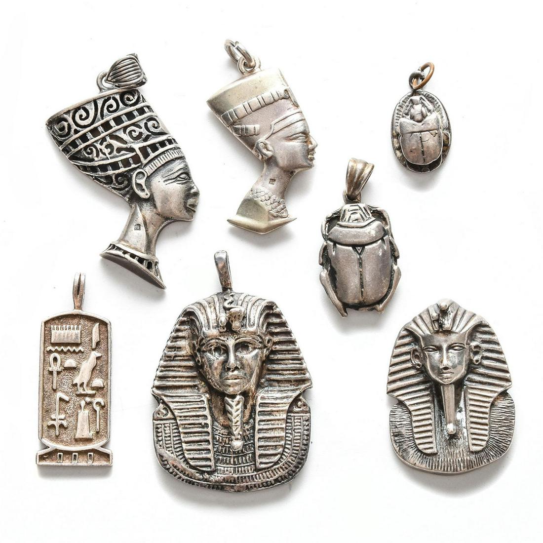 7 EGYPTIAN THEMED STERLING SILVER PENDANTS: King Tut, Nefertiti, scarabs w. hieroglyphic design. Total weight is approximately 74g. Issued: 20th c. Dimensions: 2"H, tallest Provenance: David Farin Collection