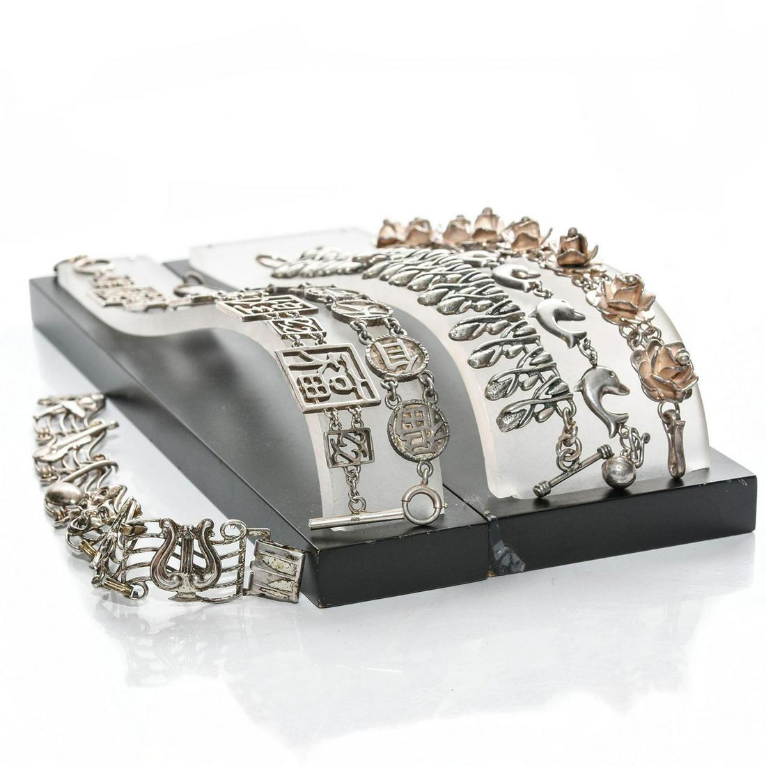 6 STERLING SILVER BRACELETS: Asian character, dolphin, music, floral designs. Each stamped sterling or 925. Total weight is approximately. 119.1g. Issued: Late 20th - Early 21st c. Dimensions: 9"L, longest Provenance: David Farin