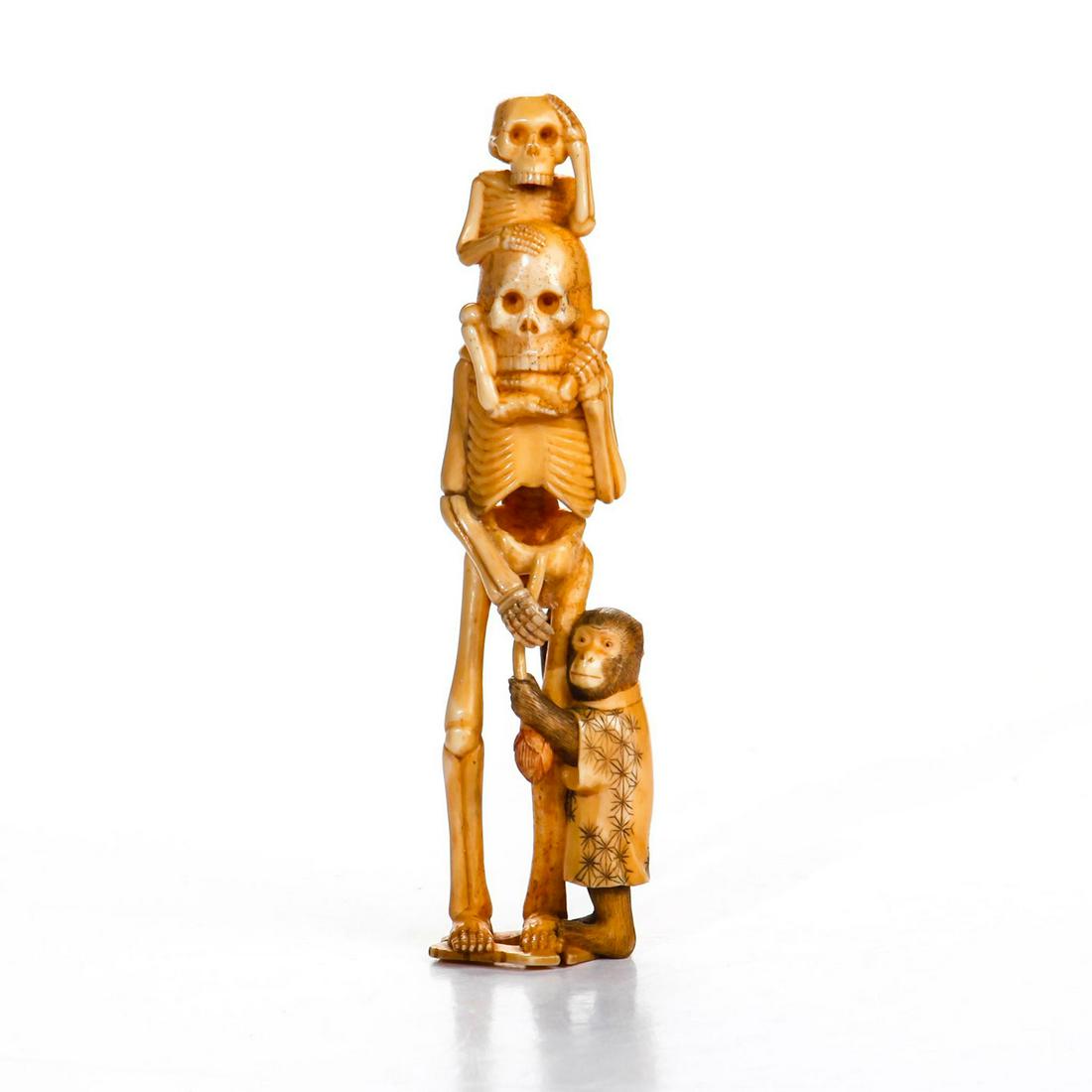 JAPANESE MEIJI PERIOD CARVED NATURAL MATERIAL OKIMONO: An unusual natural material Okimono of Skeletons. An unusual Okimono carved of a skeleton couple, the larger skeleton is carrying his/her child (also a skeleton) on their shoulder. While his/her right