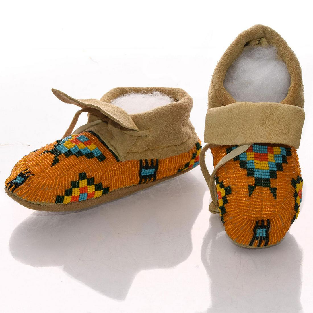 VINTAGE NATIVE AMERICAN CEREMONIAL LEATHER MOCCASINS: Soft hide. Profuse bead decoration in Native geometric designs. A vintage child's pair of Native American folk art dance soft leather hide moccasins, with extensive decorations of beads in orange, tur