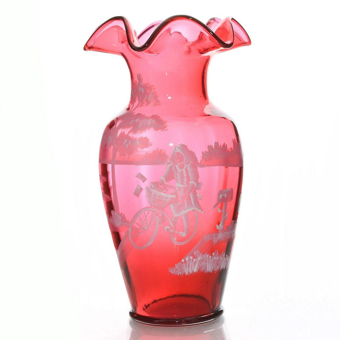 FENTON GLASS VASE, CRANBERRY MARY GREGORY STYLE: Hand painted white on ruby glass vase, girl on bicycle. The girl is riding past a mailbox and tree. The bottom is signed by artist T Neader. #596 / 2350 Issued: 20th c. Dimensions: 10"H Manufacturer: 