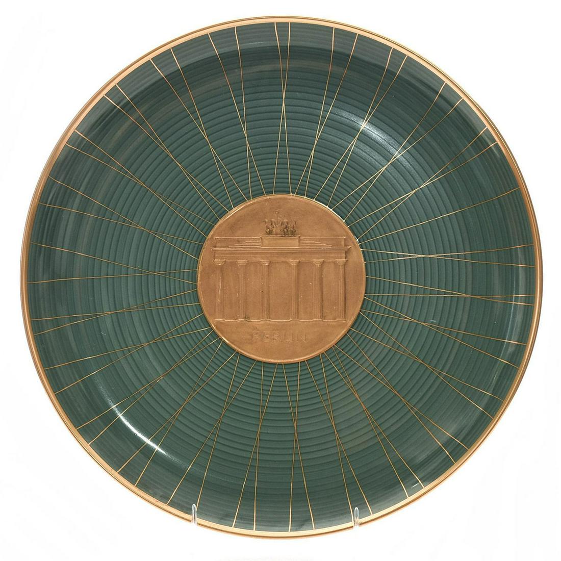 KPM BERLIN PORCELAIN BRANDENBURG GATE GILDED PLATE: Raised molded gold bisque central image, raised letters BERLIN. An exquisite 20th century glazed porcelain dinner plate, decorated with a raised and molded gilded central bisque depiction of the Brand