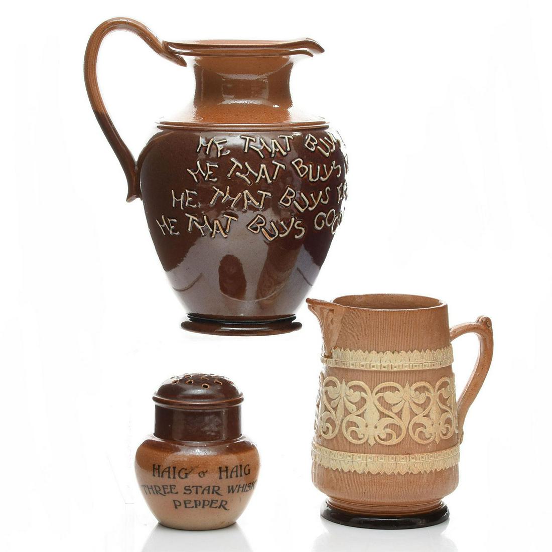 GROUP OF 3 DOULTON LAMBETH STONEWARE: 2 pitchers and advertising ware pepper shaker. One small stoneware pitcher designed with applied decorations. One medium glazed, stoneware pitcher inscribed HE THAT BUYS LAND BUYS STONES, HE THAT BUYS