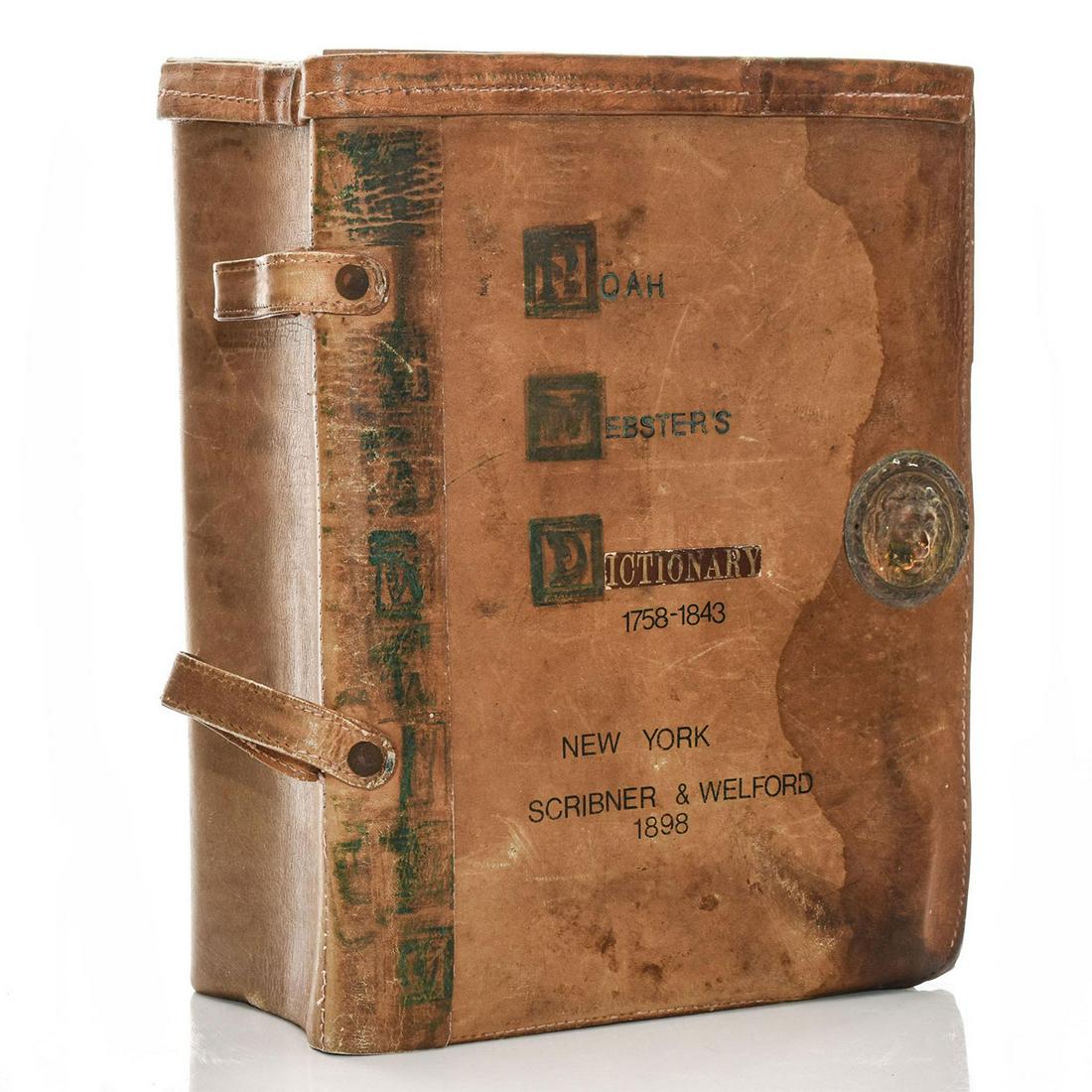 1898 NOAH WEBSTER DICTIONARY BOOK: Leather bound, with metal lion detail to front. Age and use related wear consistent with age. Issued: 1979 Dimensions: 8.5"L x 11.5"H x 4.75"D Manufacturer: Scribner & Welford Country of Origin: Unite