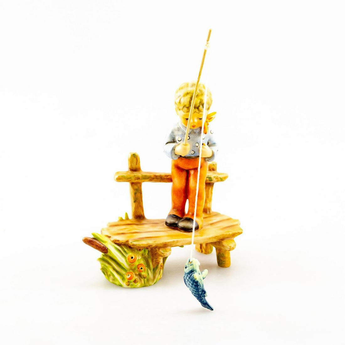 GOEBEL HUMMEL FIGURINE, THE ANGLER 566: Young boy fishing. Handcrafted; hand painted. Goebel backstamp. Artist: Gerherd Skrobek Issued: 1995 Dimensions: 7.5"H Manufacturer: Goebel Country of Origin: Germany