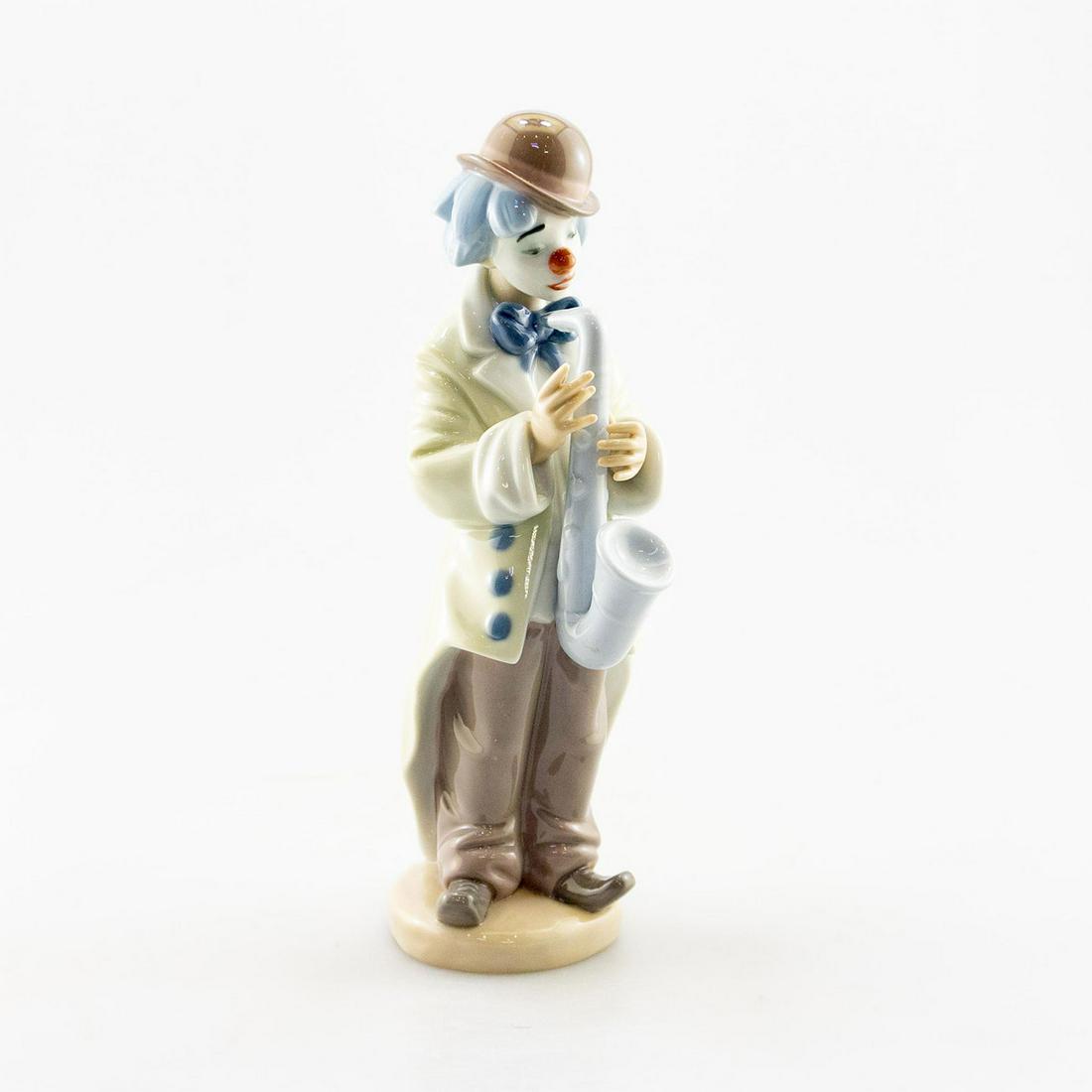 LLADRO PORCELAIN 5471, SAD SAX, CLOWN PLAYING SAXOPHONE: A clown with a sad expression playing the saxophone. Artist: Lladro Issued: 1987 Dimensions: 9.25"H Manufacturer: Lladro Country of Origin: Spain