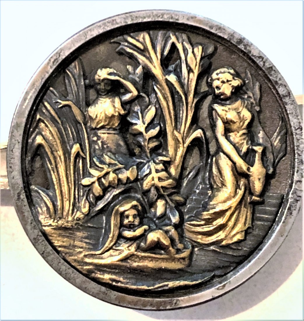 I DIV. 1 STEEL CUP BUTTON OF "MOSES IN THE BULLRUSHES": 1 Large late 19th century steel cup picture button. The example in this lot depicts "Moses among the Bulrushes", the design is brass and in good condition.