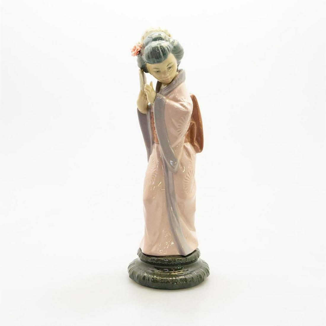 Lladro Lady Figurine, Timid Geisha 4990: Porcelain; high gloss. Japanese lady wearing a pink kimono covering her face with a fan. Hand made; hand painted. Lladro backstamp. Artist: Salvador Debon Issued: 20th c. Dimensions: 11.75"H Manufactu