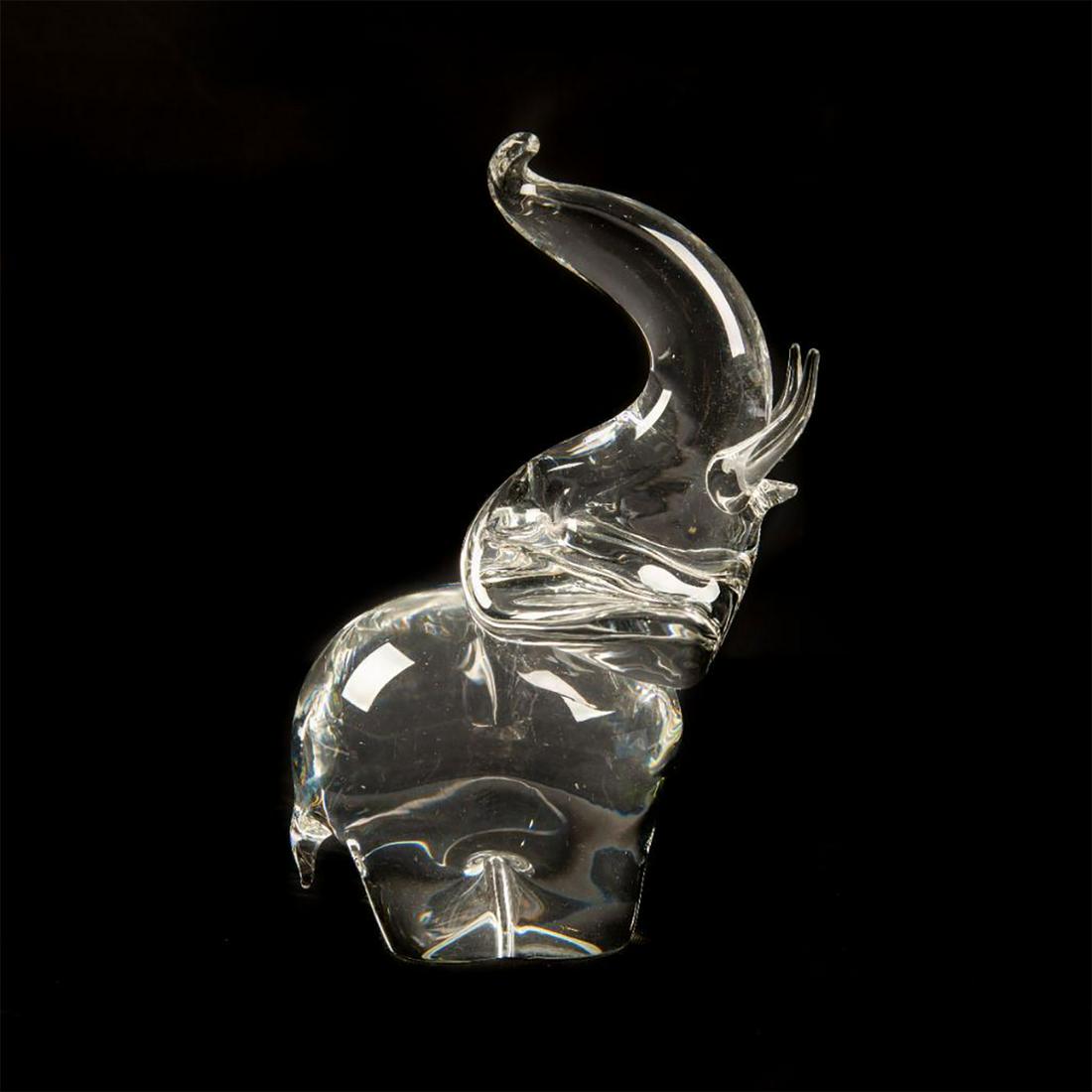 STEUBEN CRYSTAL GLASS ANIMAL FIGURE,TRUMPETING ELEPHANT: Cut crystal elephant with trunk raised upward. Etched STEUBEN on the underside. Artist: James Houston Issued: 20th c. Dimensions: 8"H x 4"W Manufacturer: Steuben Country of Origin: United States