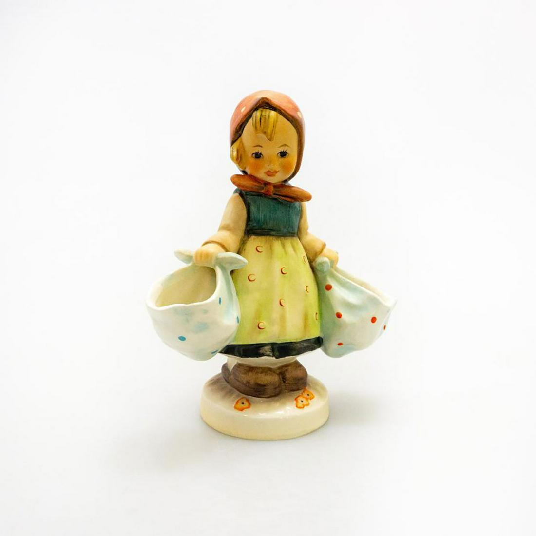 GOEBEL HUMMEL FIGURINE, MOTHER'S DARLING #175: A young lass holds two blue satchels. Issued: 20th c. Dimensions: 5.75"H Manufacturer: Goebel Country of Origin: Germany