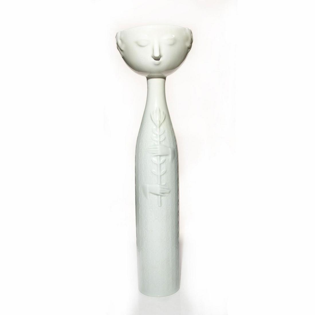 ROSENTHAL PORCELAIN LARGE EVA VASE BY BJORN WIINBALD: Glazed, white with a bottle shaped body and bowl opening. Decorated with a face and hands holding a stemmed flower in high relief decor. Possible restoration to bowl. Rosenthal backstamp. Artist: Bjor