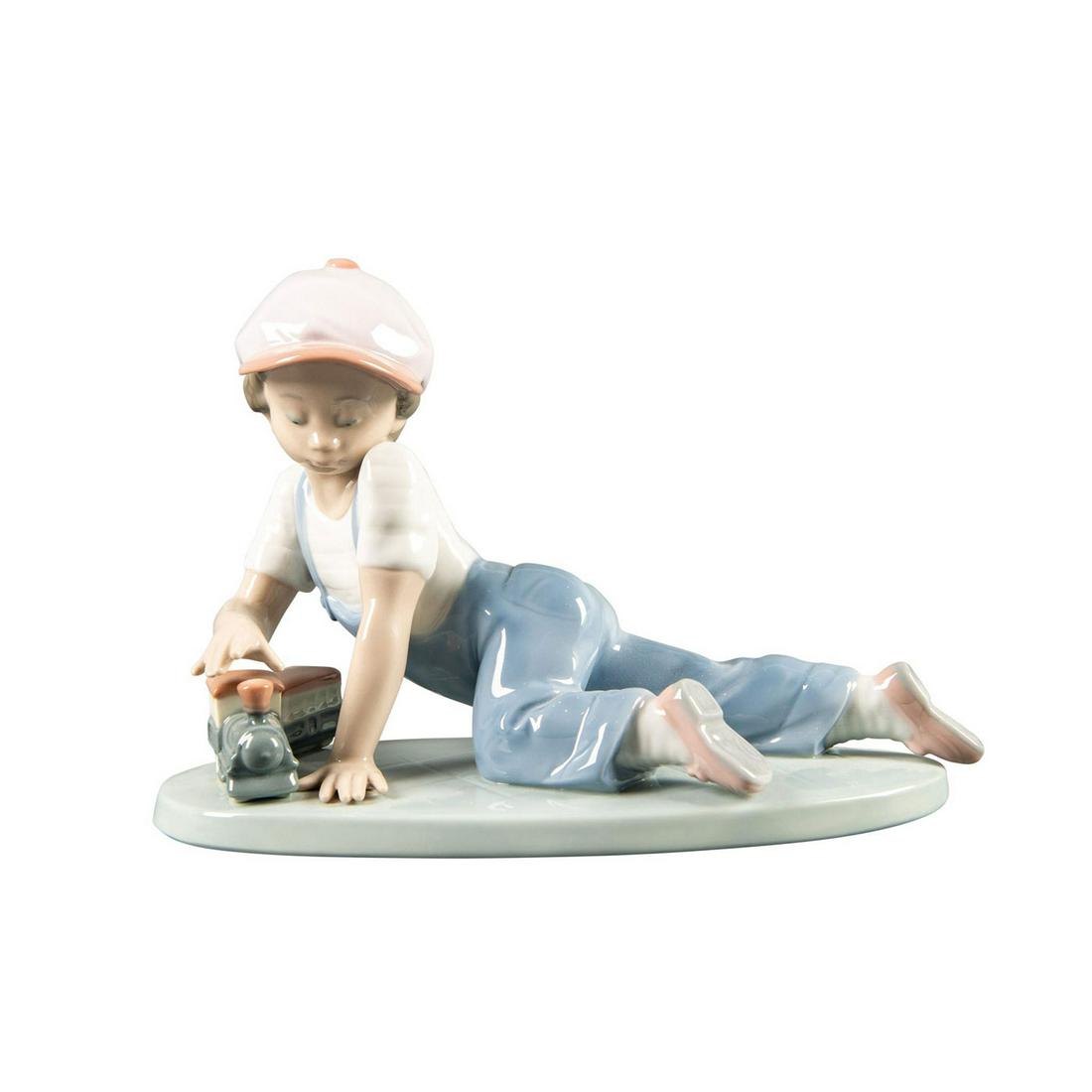 Lladro Figurine, All Aboard 01007619: Collectors Society piece. Porcelain; hand painted. Young boy w. toy train. Lladro backstamp. Includes original box. Artist: Antonio Ramos Issued: 1992 - 1995 Dimensions: 7.5"W5"H Manufacturer: Lladro 