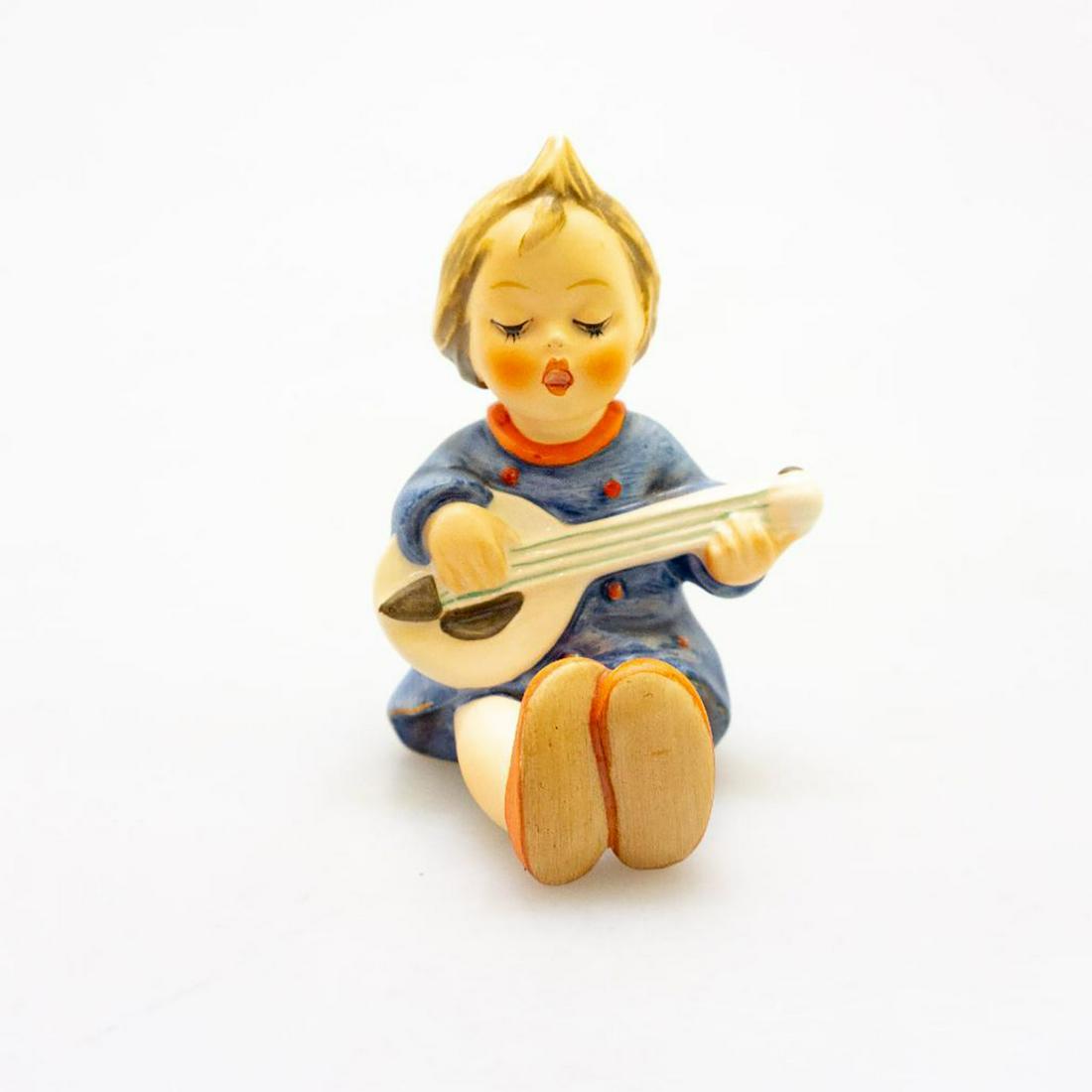 Rare Goebel Hummel Figurine, Joyful #53: A rosy-cheeked lass sits singing and playing her lute. Issued: 20th c. Dimensions: 4"H Manufacturer: Goebel Country of Origin: Germany