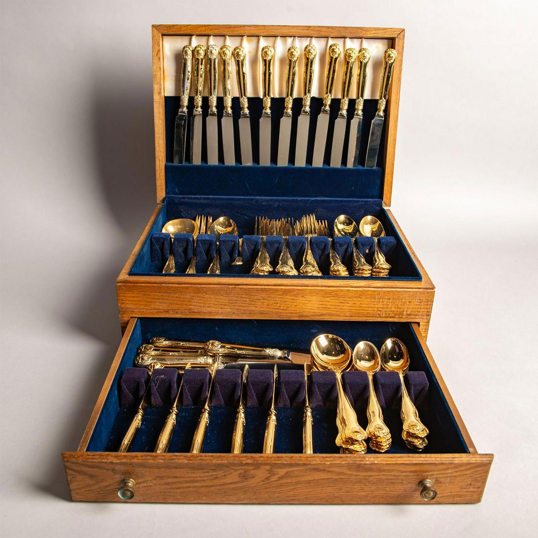 Roberts And Belk 84Pc Gold Plated Flatware Set: Collectible flatware service with the Royal Husk pattern. Housed in a blue velvet lined wooden case. Includes dinner knives, dinner forks, place spoons, cream soup spoons, salad forks, butter spreader