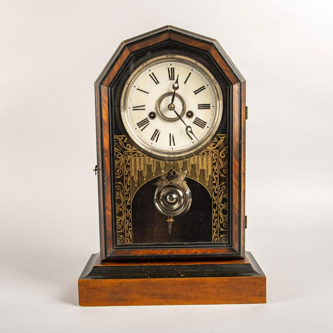 Antique E Ingraham Pendulum Mantel Clock: Mantel clock housed in carved wooden frame. Ornate loose pendulum. Interior has manufacturer's stamp. Patented Oct 1878 can be read on clock. Front glass has an applied gold design. Untested. Issued: 
