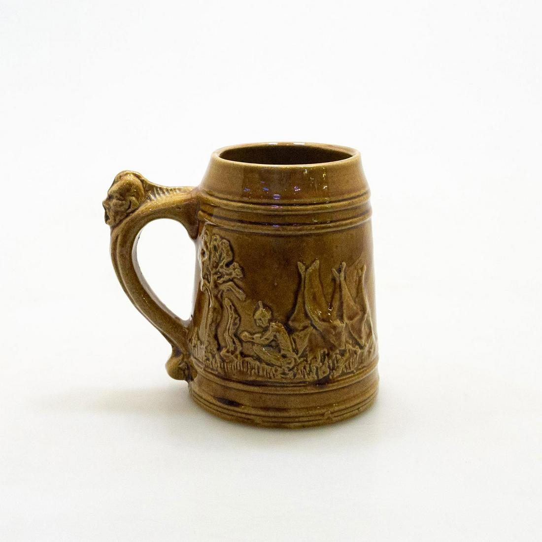 Sleepy Eye Pottery Tankard: This brown stoneware tankard made by Weir pottery company. Indian Chief decorated one side and tepee decor on reverse. Handle has indian head decoration Issued: 20th century Dimensions: 5.5"H x 4" dia