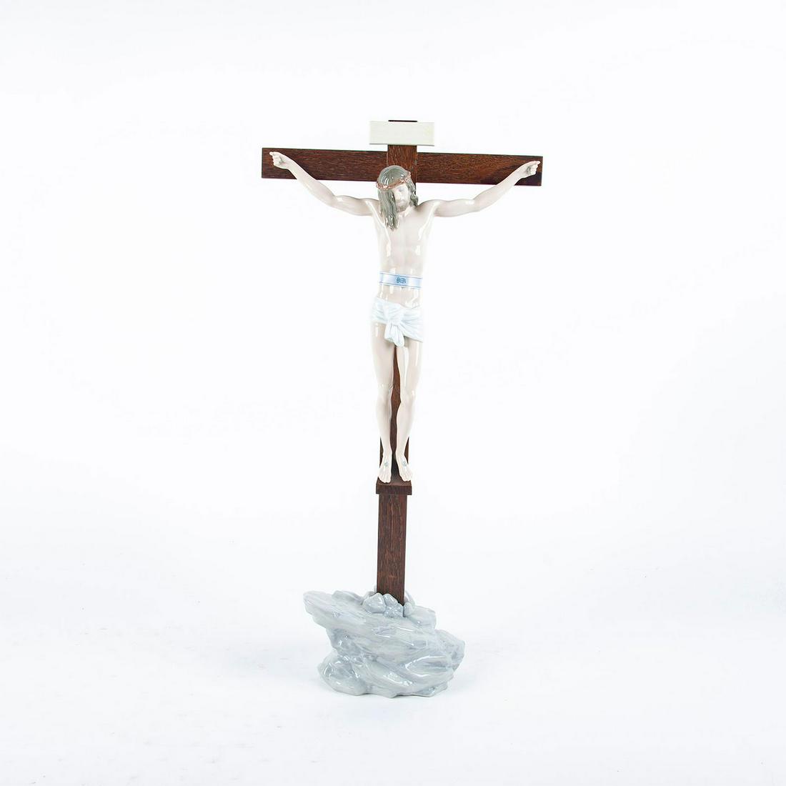 Lladro Porcelain Figurine, Our Savior Crucifix 01006911: Porcelain; gloss finish. Depicts Jesus Christ on a wooden cross. W. box. Lladro backstamp. Artist: Jose Javier Malavia Issued: 2003 Dimensions: 23.5"H Manufacturer: Lladro Country of Origin: Spain Con